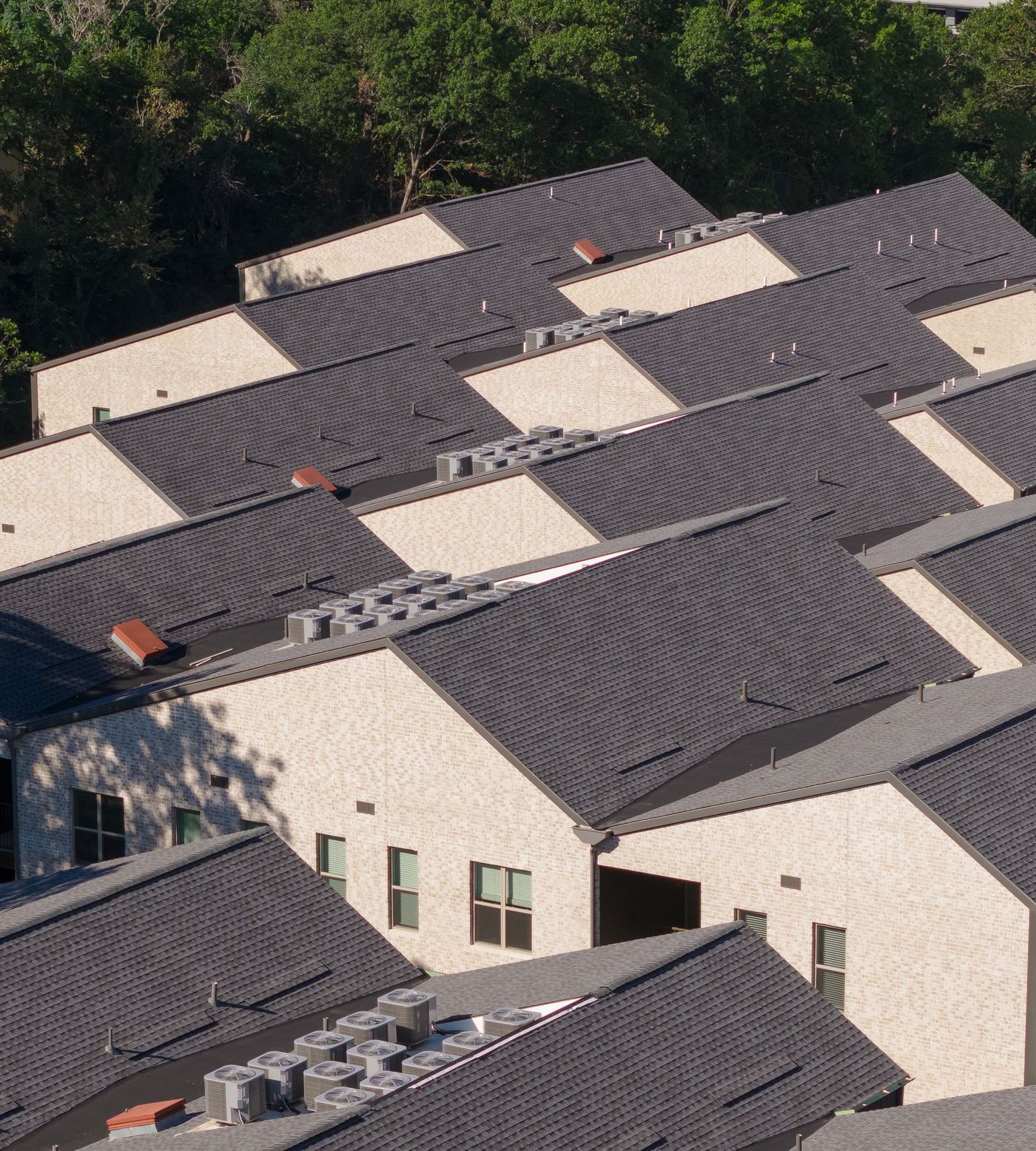 Aerial view of gabled-roof attainable housing set among mature trees in Southern Dallas